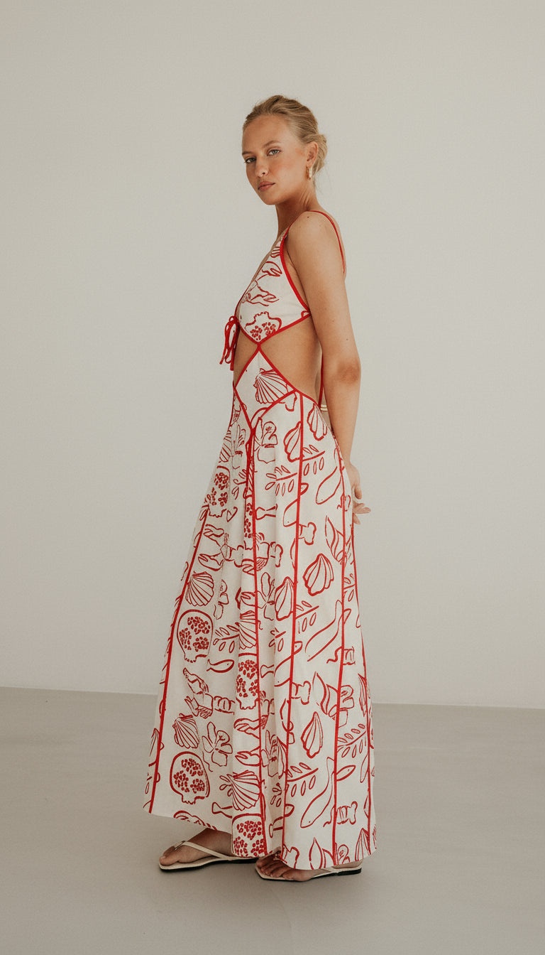 Isadora London Ophelia Maxi Dress – elegant white maxi with red coastal print and waist cut-outs, made for effortless summer style.