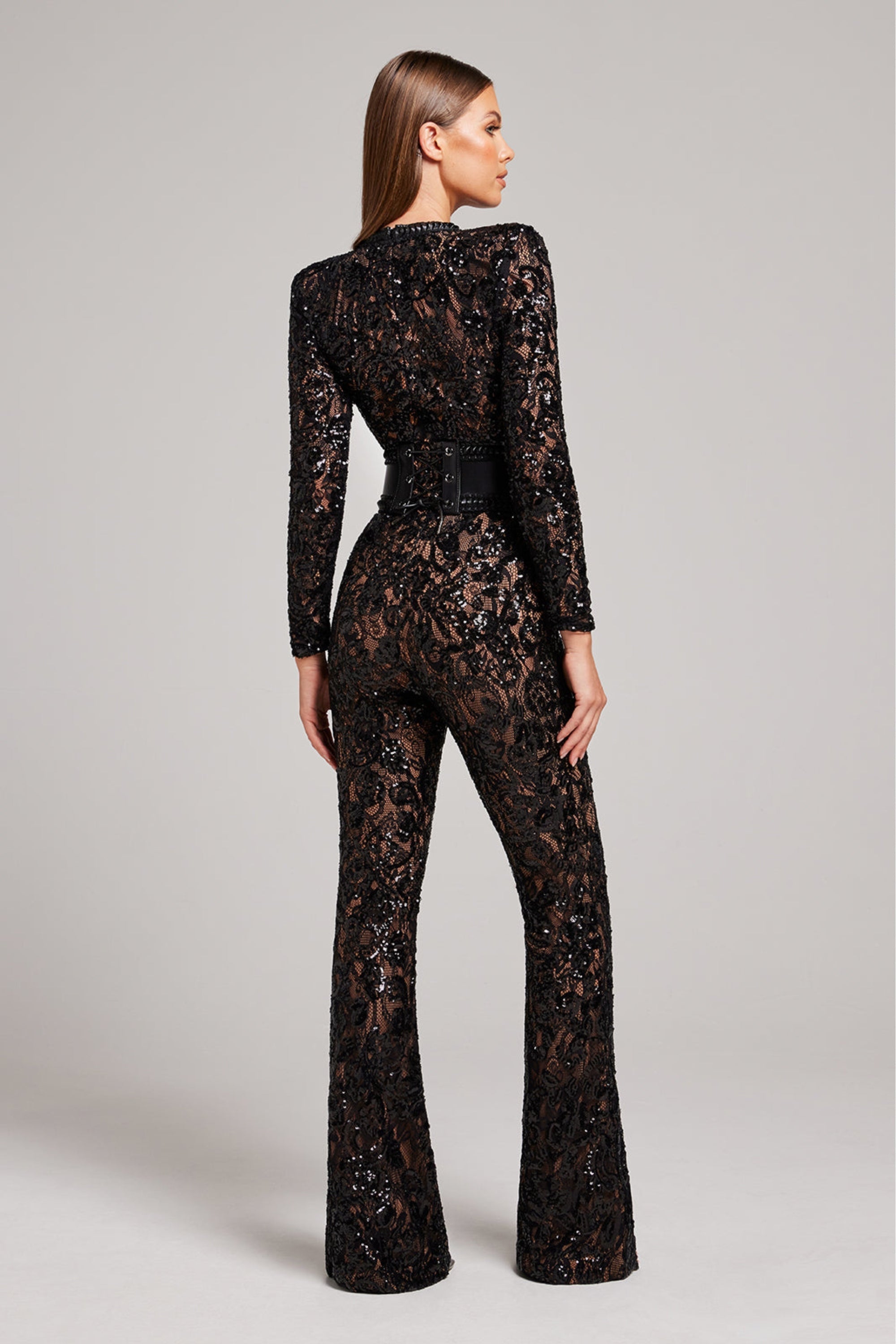 Back view of the black lace tailored jumpsuit showing sheer lace pattern and sculpted fit.