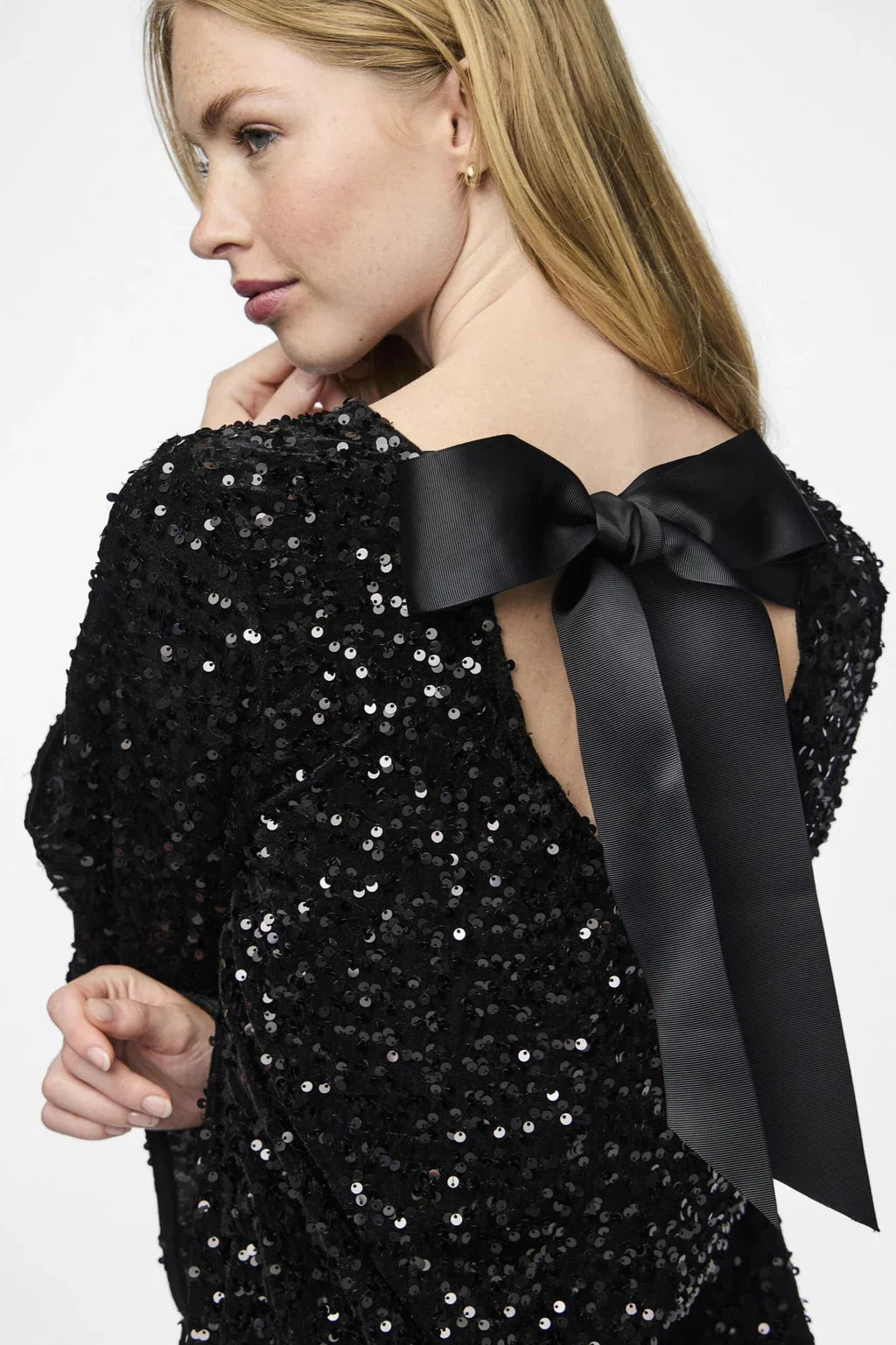 Close-up bow-back on black glitter mini – oversized bow detail – Isadora London.