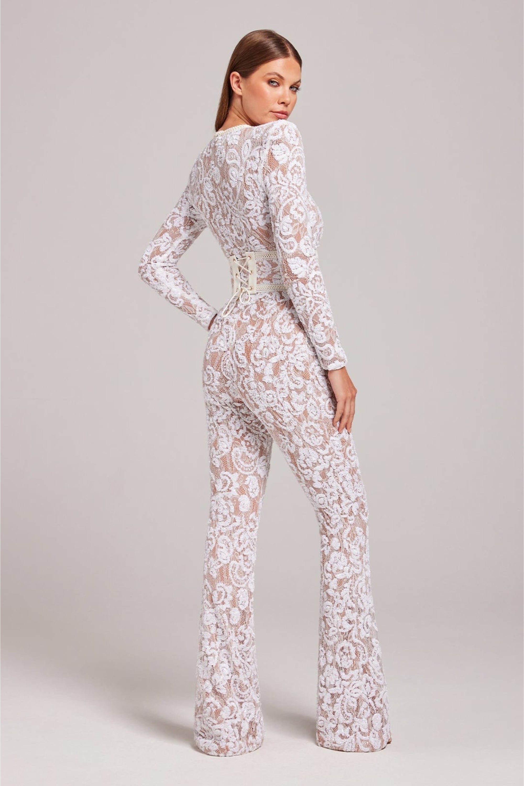 Angled front view of the white floral lace tailored jumpsuit with long sleeves and fitted waist.