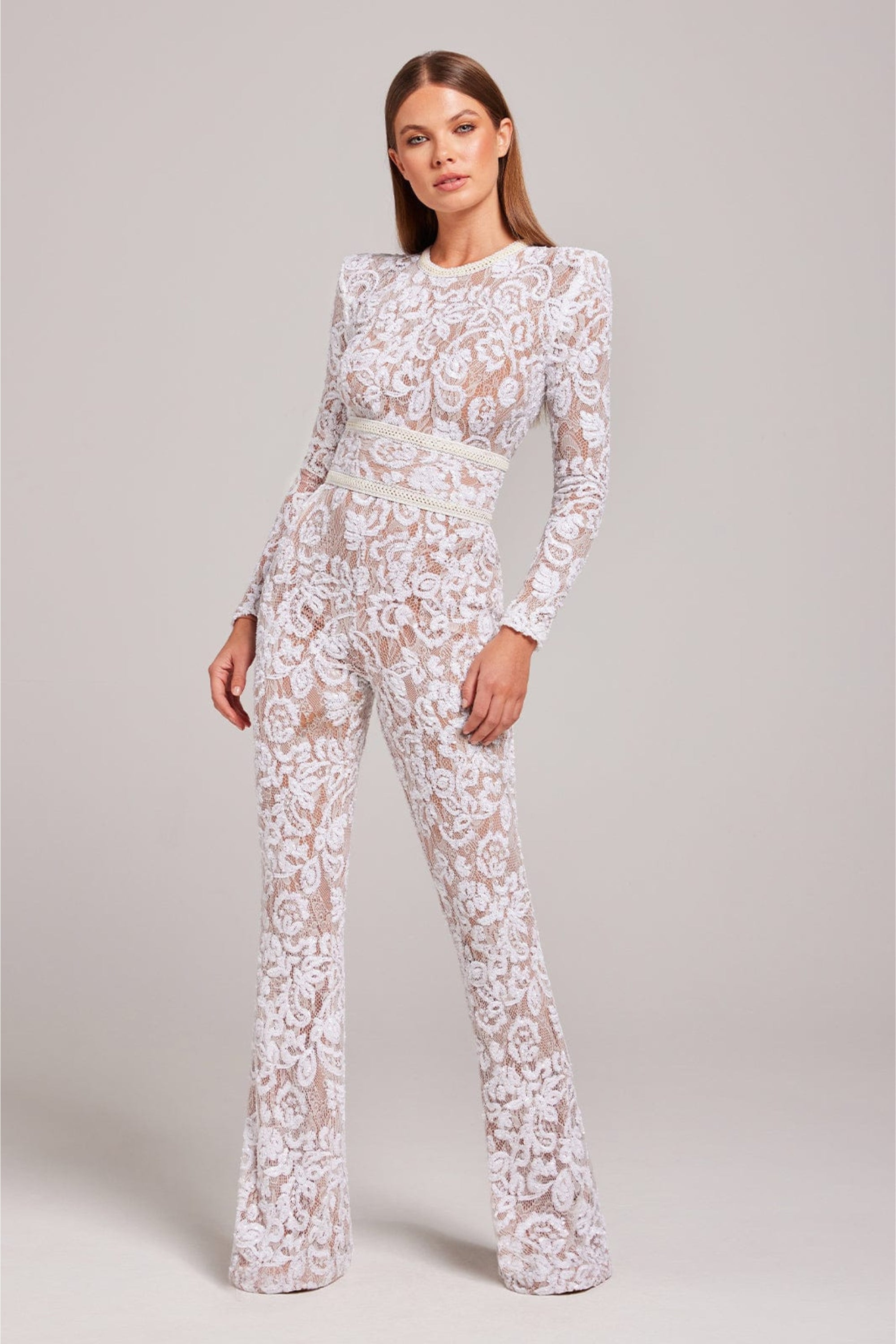 Model wearing the white tailored lace jumpsuit, full front view with fitted silhouette and floral lace detailing.