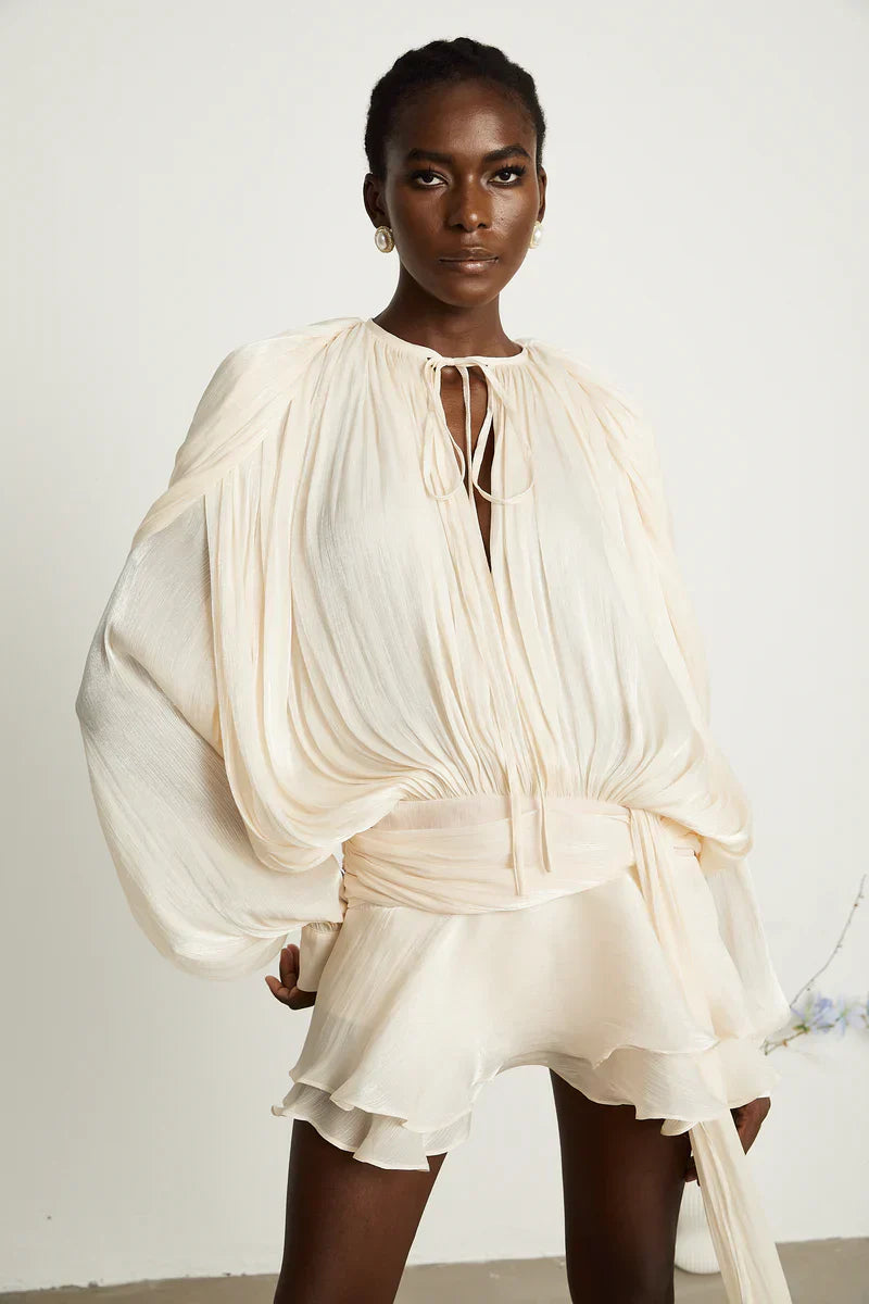 Model wearing apricot Luxe Flowy Mini Dress by Isadora London – elegant summer style