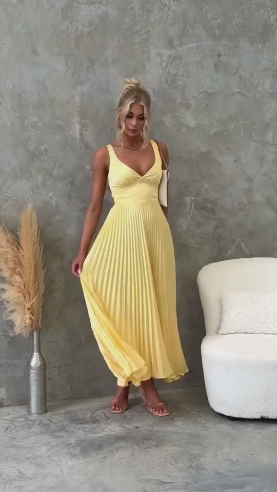 Model wearing the Isadora™ Yellow V-Neck Maxi Dress – elegant pleated summer dress with a flattering wrap neckline and flowy silhouette, perfect for weddings, garden parties, and sunny days.