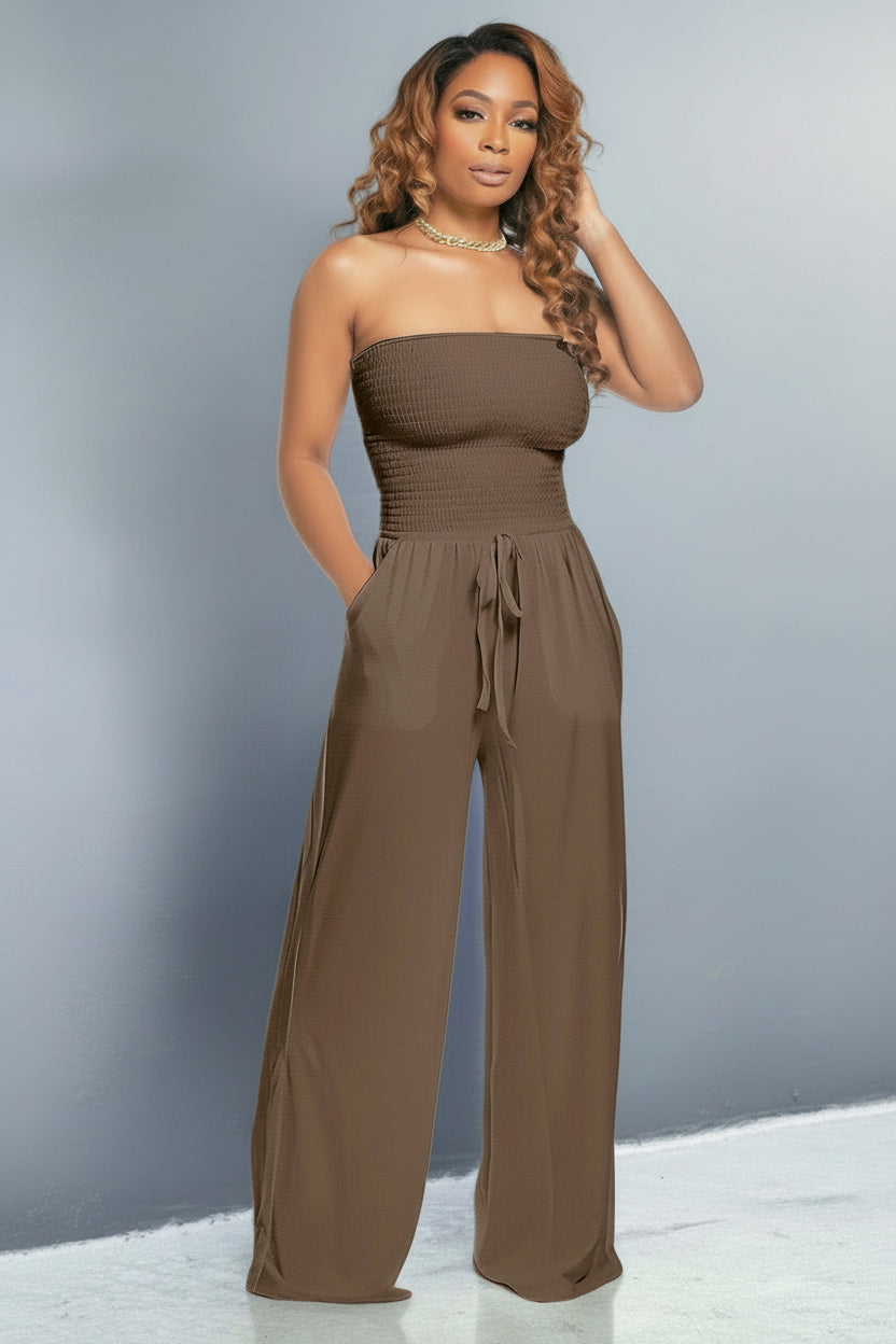 Model wearing a brown off shoulder jumpsuit with smocked bodice, wide-leg fit and tie-waist – casual and flattering style.